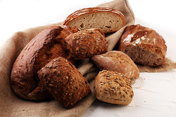 Different kinds of bread and bread rolls on board from above. Kitchen or bakery poster design.