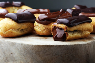 Traditional French dessert. Eclair with chocolate icing. Wooden background