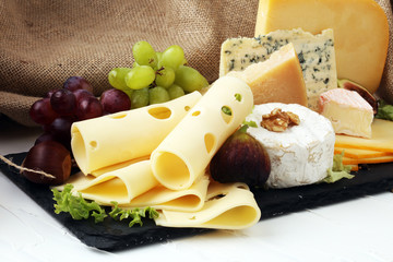 Cheese platter with different cheese, fig, salad and grapes
