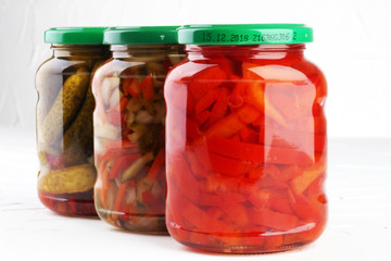 Jar with variety of pickled vegetables. Carrots, field garlic, cucumber in glas. Preserved food