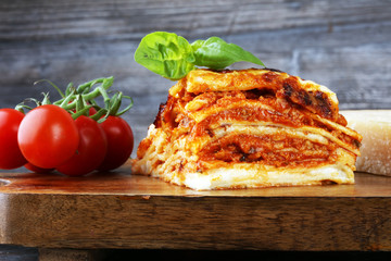 Serving of spicy traditional Italian beef lasagne in a restaurant - bolognese sauce topped with basil leafs