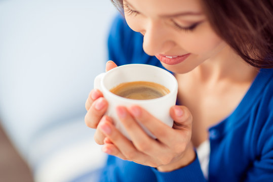 Great beginning of the day! Cropped close up photo of relaxed attractive lady, resting and drinking coffee, wearing blue casual outfit