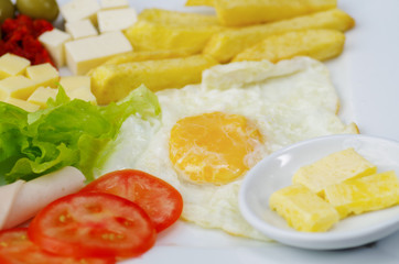 Close up of a delicious fresh mediterranean luch with egg, lettuce, ham tomato, cheesse, fried potato and somes olives on a wooden table