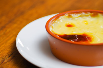 Close up of a Turkish traditional dairy style rice pudding sutlac served in a crock on wooden table