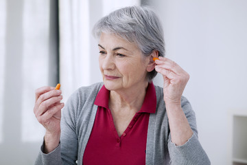 Senior woman using ear plugs