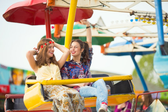 Two teenage girls are enjoying their ride at an amusement park