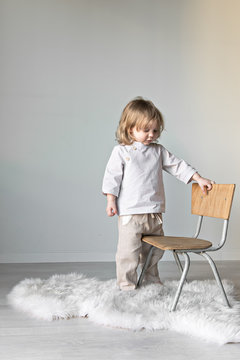 kleines Kind spielt zuhause mit einem Stuhl
