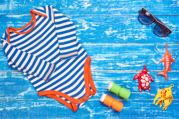 Baby Child summer stuff to the beach on a blue wooden background. Top view with copy space for text.