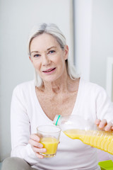 Senior woman pouring herself a glass of orange juice