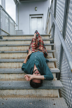Man lying on stairs with eyes closed
