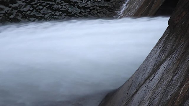 Vista lateral de enorme chorro de agua saliendo  en el punto de evacuacion de una presa o dique de embalse 
