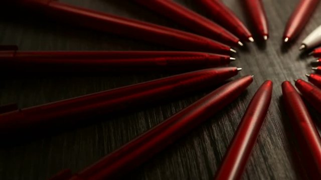 A lot of red pens and one white move in a circle. Concept office or school, knowledge day, the first of September. Video footage is spinning rotate