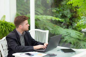 businessman and smiling, as he work on his laptop in the living room.