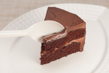 Dark chocolate cake on white plate with spoon