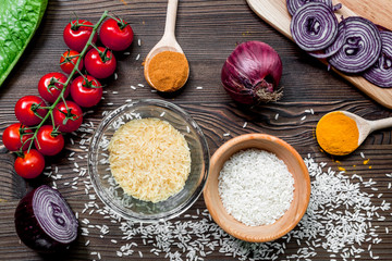 rice, spices and vegetables for paella on wooden desk background top view