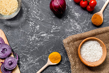rice, spices and vegetables for paella on dark desk background top view mock-up