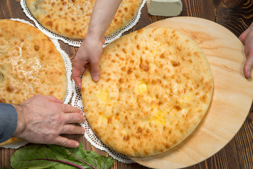 Baker's hands folded Ossetian pie on the table