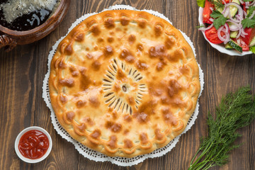 Delicious pie on the table next to the vegetables and kvass