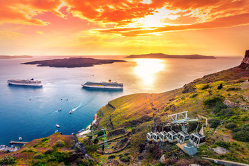 Amazing evening view of Fira, caldera, volcano of Santorini, Greece with cruise ships at sunset. Cloudy dramatic sky.