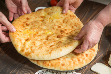 Baker's hands folded Ossetian pies on the table