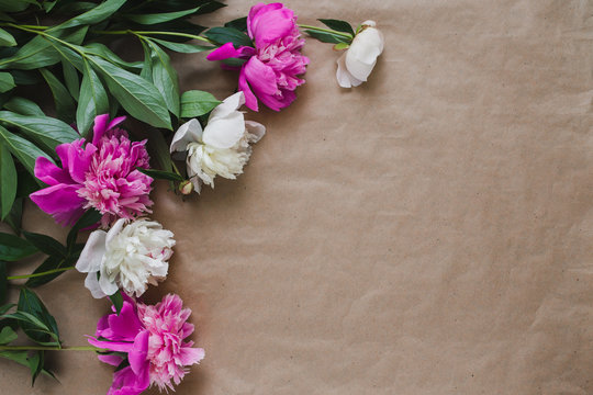 Delicate flowers on the photo of the craft paper. White and pink peonies lie on the table