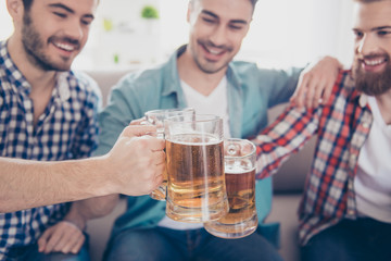 Cheers! Close up cropped photo of happy handsome men celebrating victory and clinking glasses of beer. They are fans of sports games as football, basketball, hockey, baseball