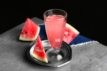 Plate with refreshing drink in glass and watermelon slices on table