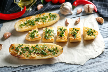 Tasty bread slices with grated cheese, garlic and herbs on parchment