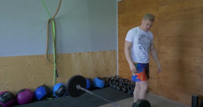 Muscular man doing the crossfit exercise in the gym. strong crossfit athlete in the middle a heavy snatch lift in a cross-fit box gym. One handsom man lifting barbel. Crossfit fitness gym