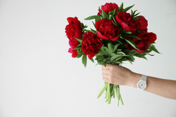 Female hand holding peony bouquet on white background