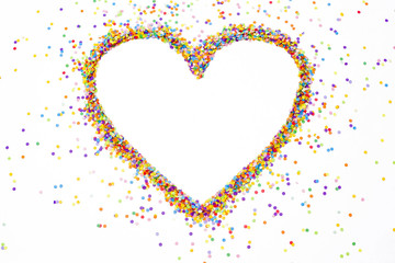 Heart made of colored confetti. Small circles of colored paper. White background. View from above. Colored heart.