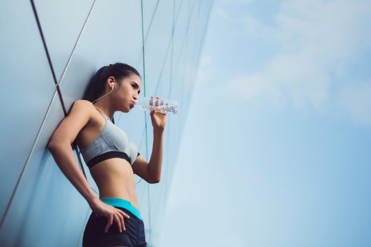 Asian Woman Relaxing And Drink Water From The Exercise.