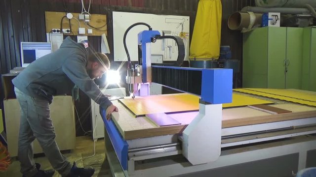 Milling cnc cuts the plastic panel hpl. The cnc operator observes the work of the machine.