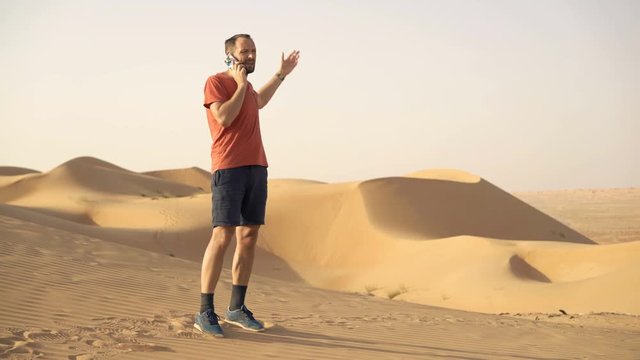 Angry, lost man talking on cellphone walking on desert
