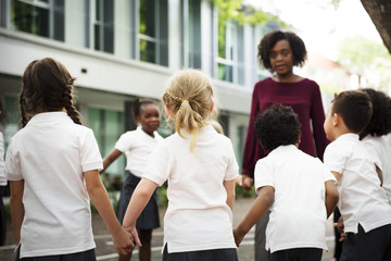 Group of diverse kindergarten students standing holding hands together