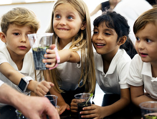 Group of diverse kindergarten students learning planting experiment in science laboratory class