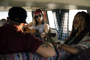 Woman Playing Guitar on Road Trip with Friends Together