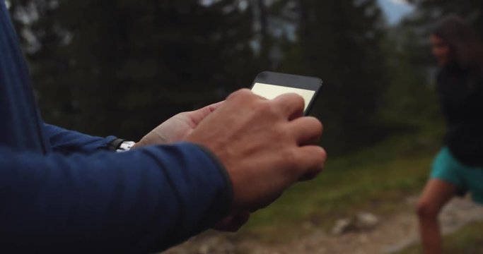 man orienting by using GPS maps technology on smartphone. Group of friends summer adventure journey in mountain nature outdoors. Travel exploring Alps, Dolomites, Italy. 4k slow motion 60p video