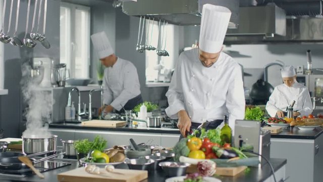 Famous Chef and His Staff Working in a Big Restaurant Kitchen. Place Has Clean Modern Design. Shot on RED EPIC-W 8K Helium Cinema Camera.