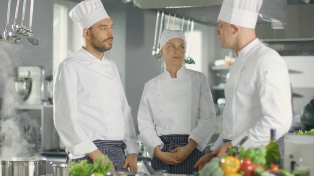 In the Modern Kitchen Team of Cooks Have Discussion. Kitchen is Full of Food Ingredients, Vegetables, Meat, Boiling Soup. Shot on RED EPIC-W 8K Helium Cinema Camera.