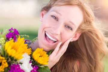 Naklejka premium Outdoor Portrait of an Excited Young Adult Brown Eyed Woman Holding a Bouquet of Flowers.