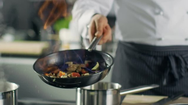 Professional Chef Cooks Flambe Style. He Prepares Dish in a Pan with Open Flames. He Works in a Modern Kitchen with Different Ingredients Lying Around.  Shot on RED EPIC-W 8K Helium Cinema Camera.