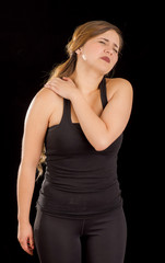 Beautiful young woman suffer from shoulder pain in a black background