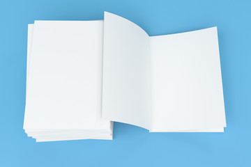 Stack of blank white closed and one open brochure mock-up on blue background