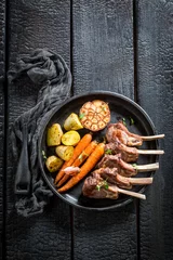 Gardinen Tasty roasted lamb ribs with thyme on dark background © shaiith