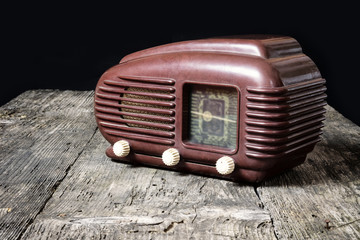 Side view of old radio standing on the old wooden desk. Edited as a vintage photo with dark edges. ...