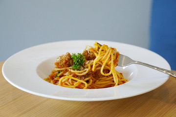 Spaghetti Bolognese with meatballs and tomato sauce topped with parsley.