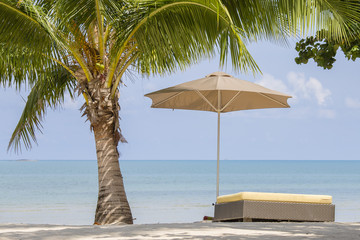 Beautiful tropical beach, palm tree, sea water, umbrella and sunbed on a sunny day. Thailand