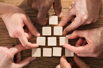 People Arranging Block On Pyramid
