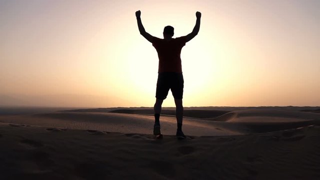 Silhouette of successful man standing on desert during sunset, super slow motion 240fps
